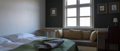 A bedroom with a bed, a bench by the window, and a chair.