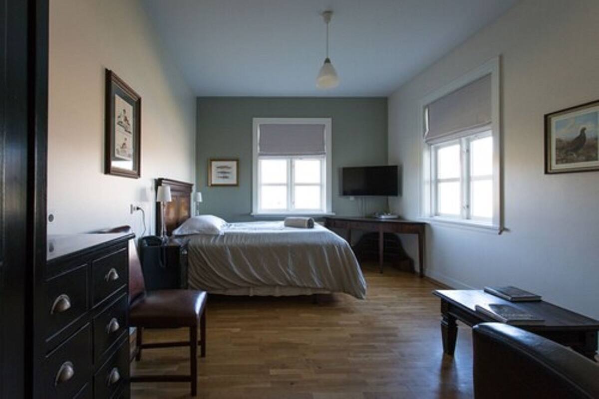 Un dormitorio con cama, escritorio, silla y televisor.