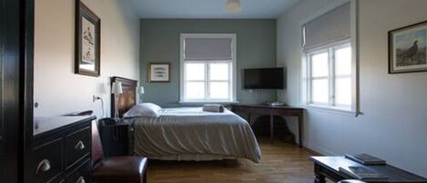 A bedroom with a bed, a desk, a chair, and a television.