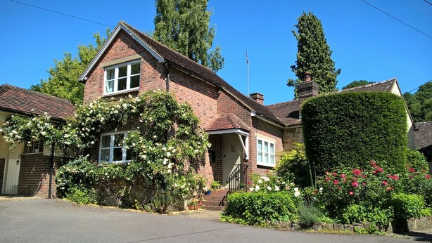 A two-story brick house with a front porch, a garage, and a well-maintained garden with roses. - Charming English cottage, Ashdown Forest, excellent pub (Danehill)