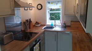 A modern kitchen with a stainless steel range hood, a sink with a dish rack, and wooden cabinets. - Charming English cottage, Ashdown Forest, excellent pub (Danehill)