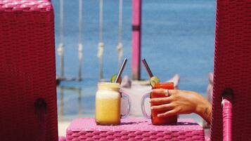 A beach scene with two wicker chairs and a table.