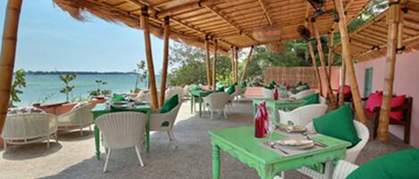 An outdoor seating area with wicker furniture and a view of the sea.