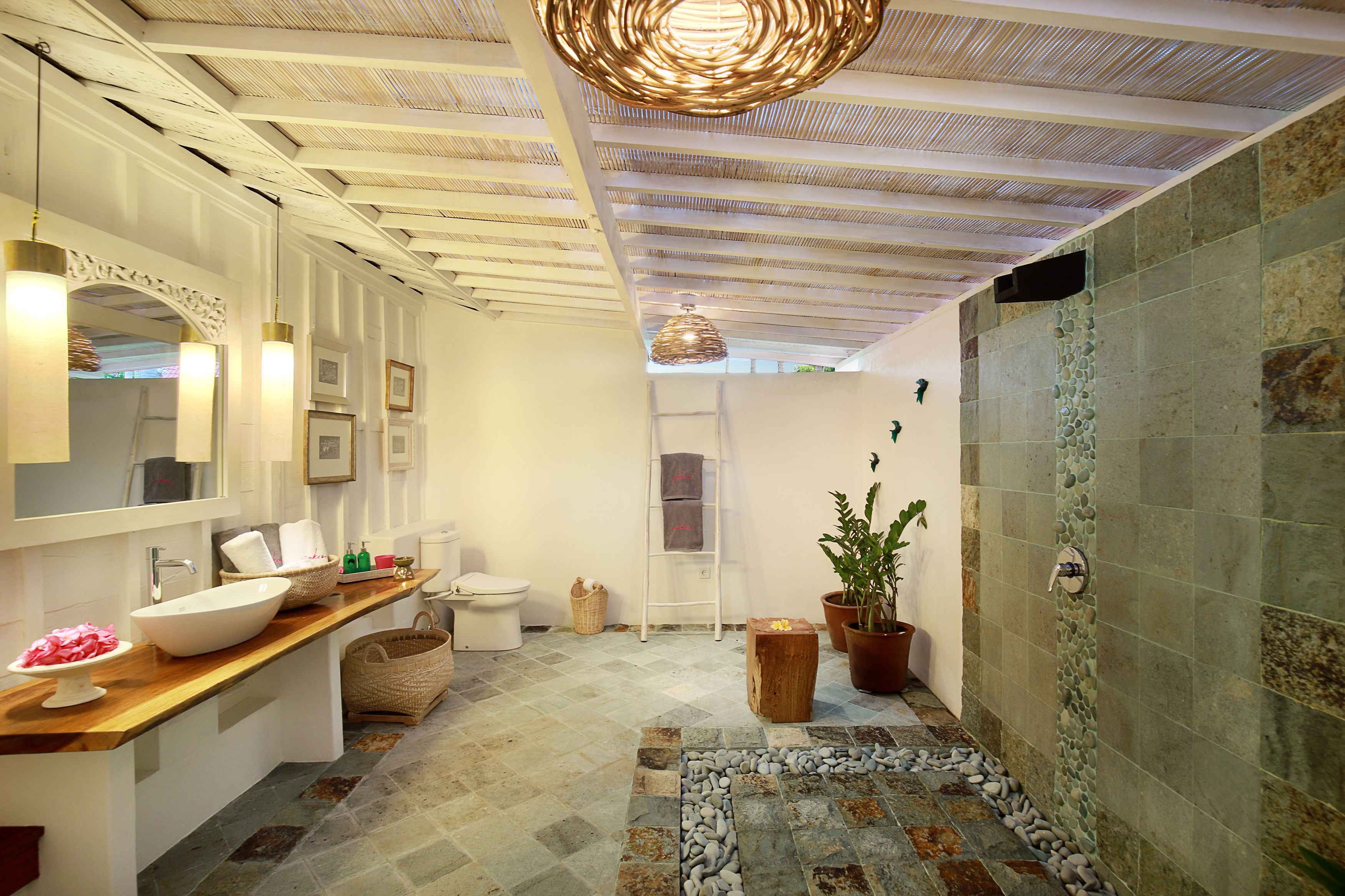 A modern bathroom with a large sink, mirror, and a stone wall shower area.
