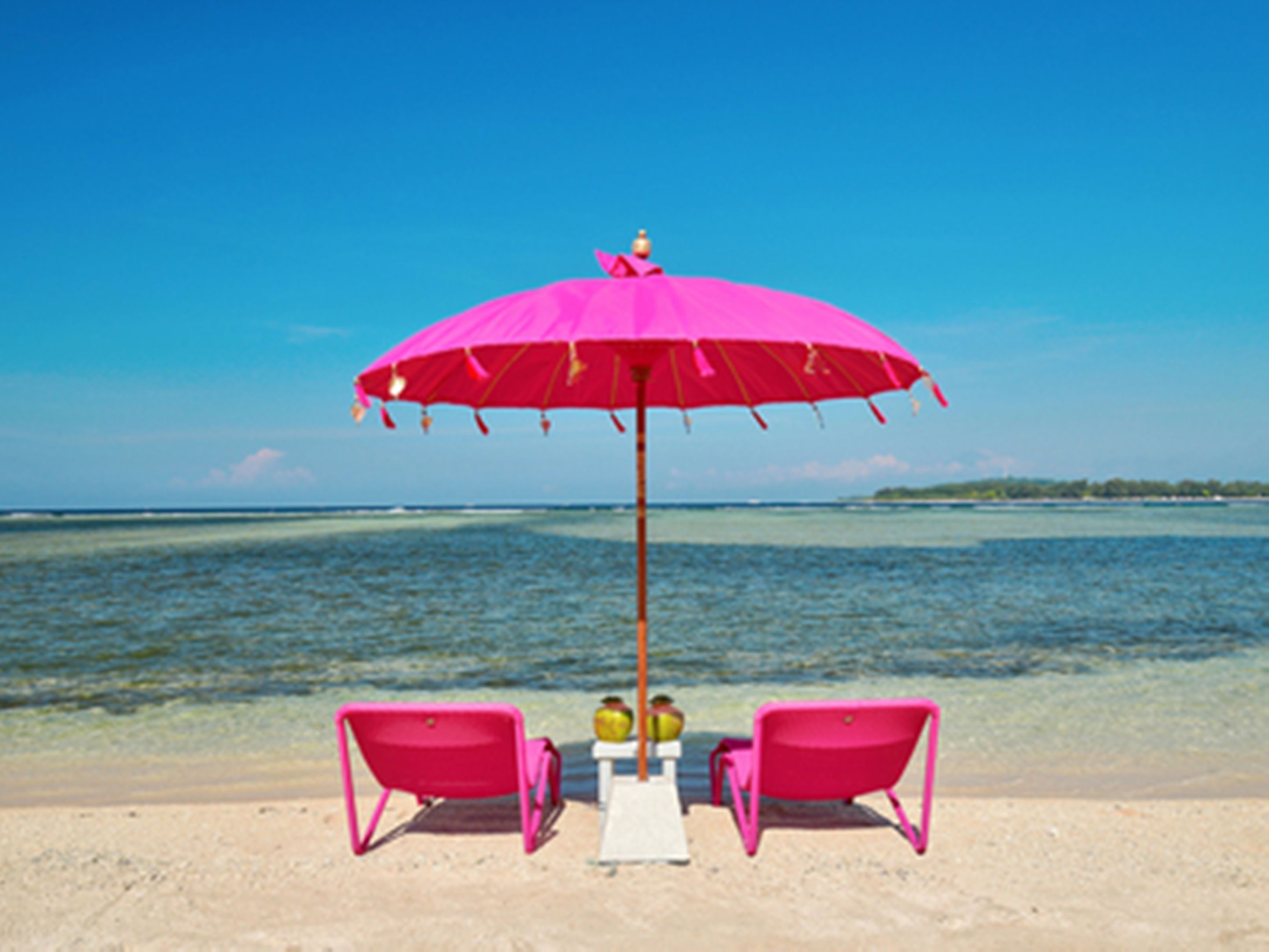 A beach scene with a pink umbrella and two pink chairs.