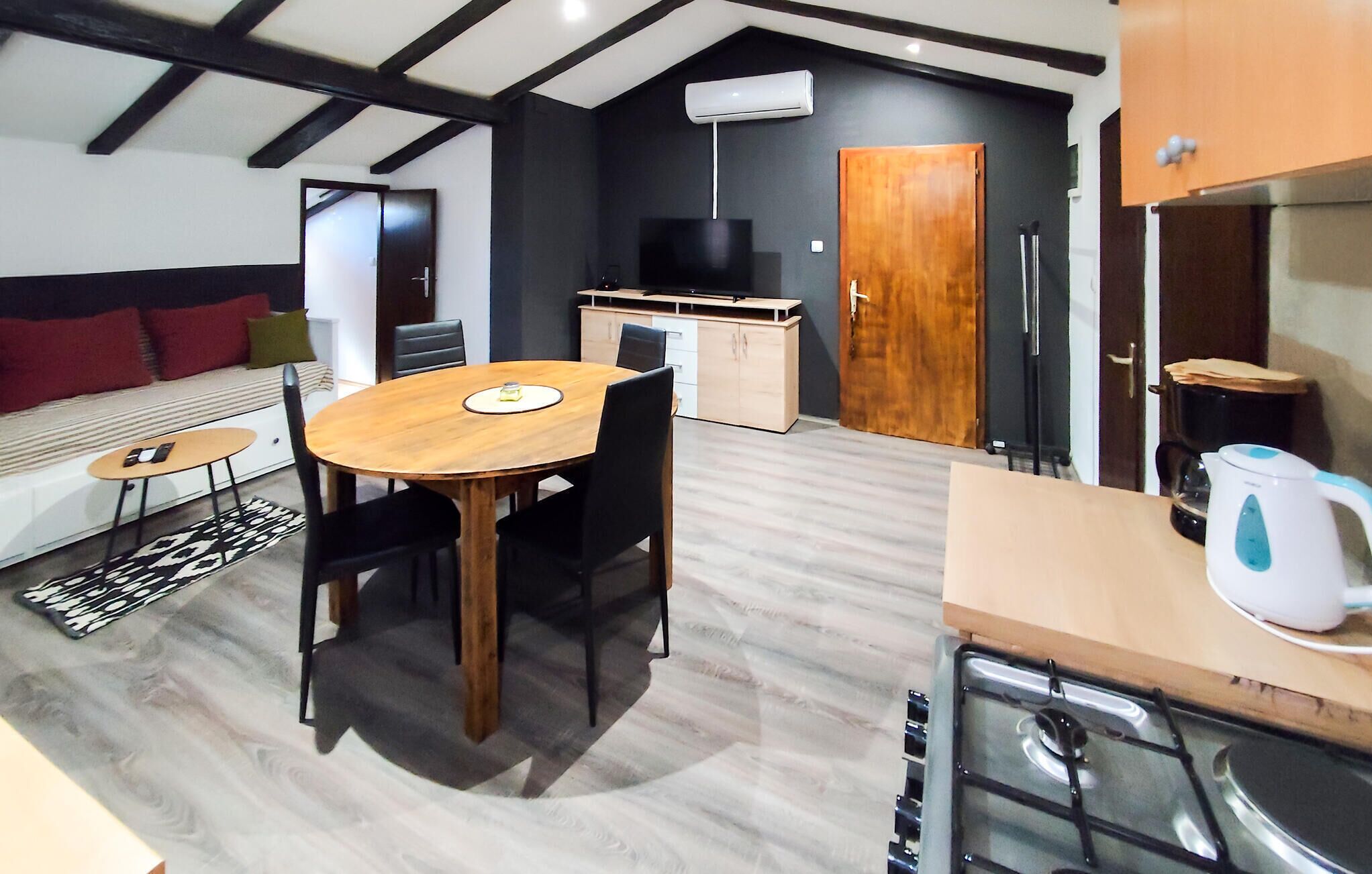 Un espace de vie compact comprenant un coin repas, une kitchenette et un canapé avec des coussins.