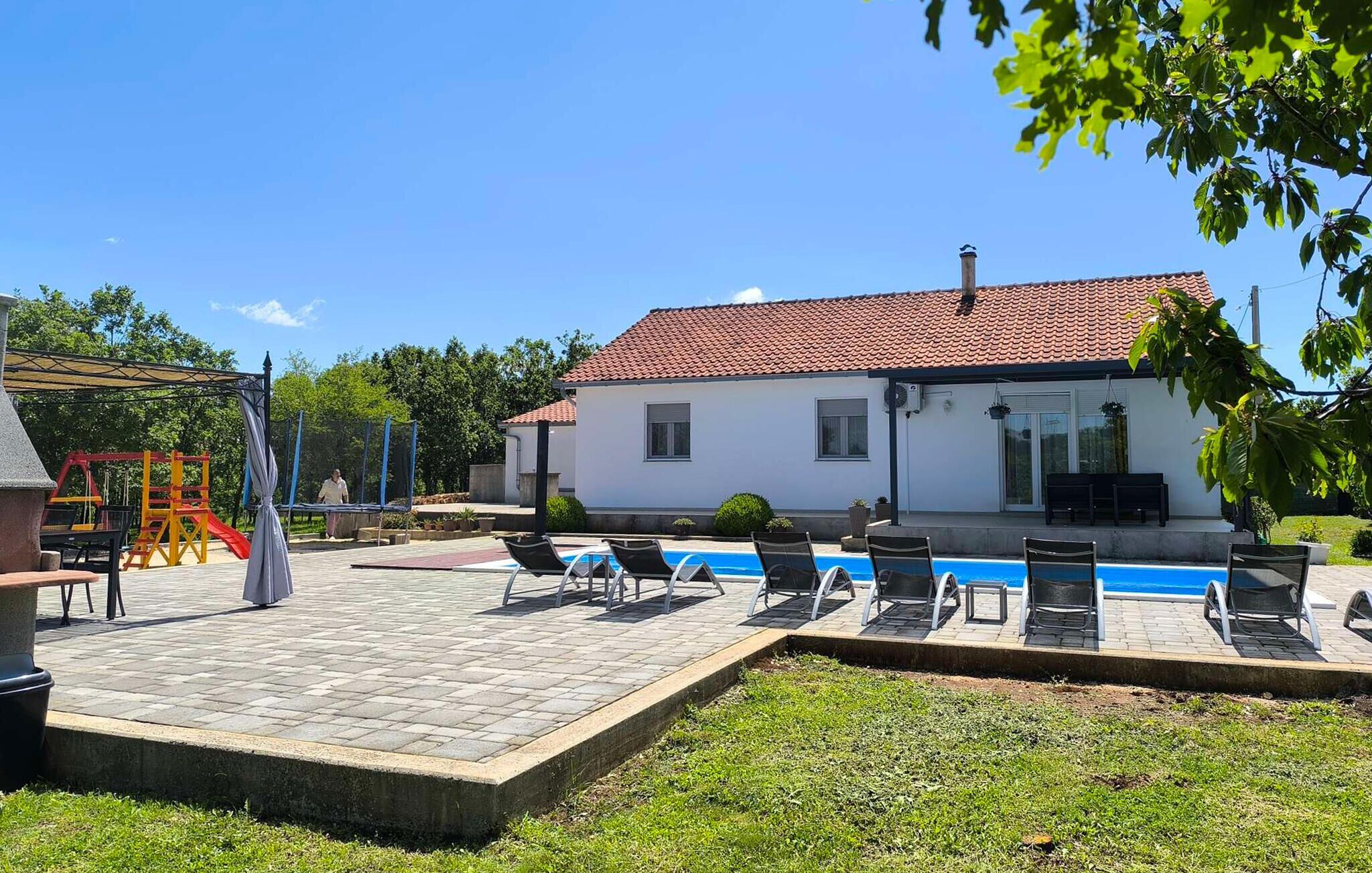 A house with a swimming pool, outdoor seating, and a playground.