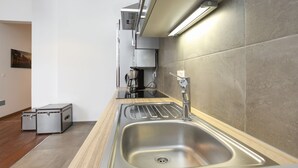 A modern kitchen with a stainless steel sink, a coffee machine, and a compact refrigerator.