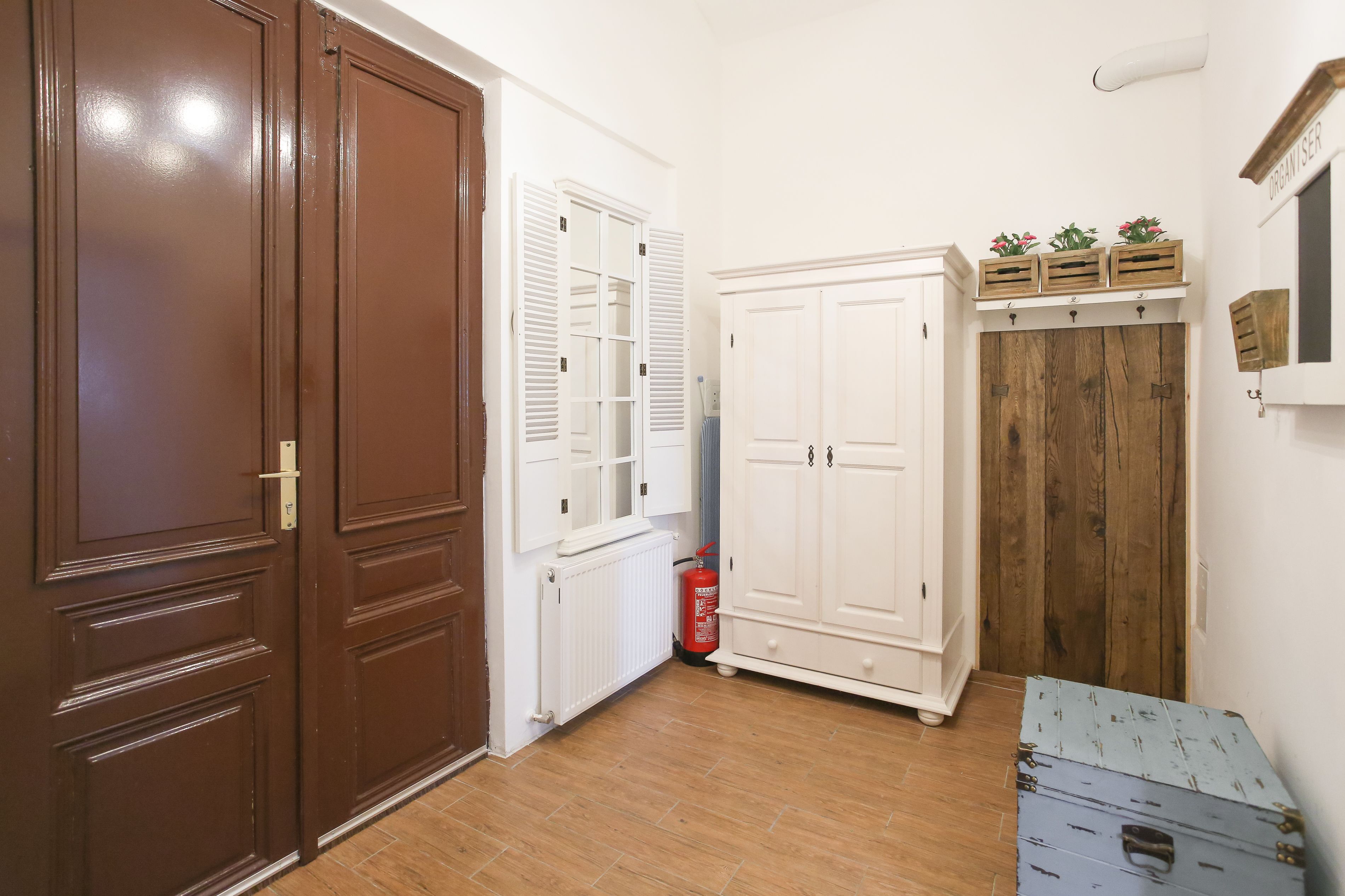 Ein Korridor mit einer braunen Tür, weißen Schränken und einem Holzgarderobe.