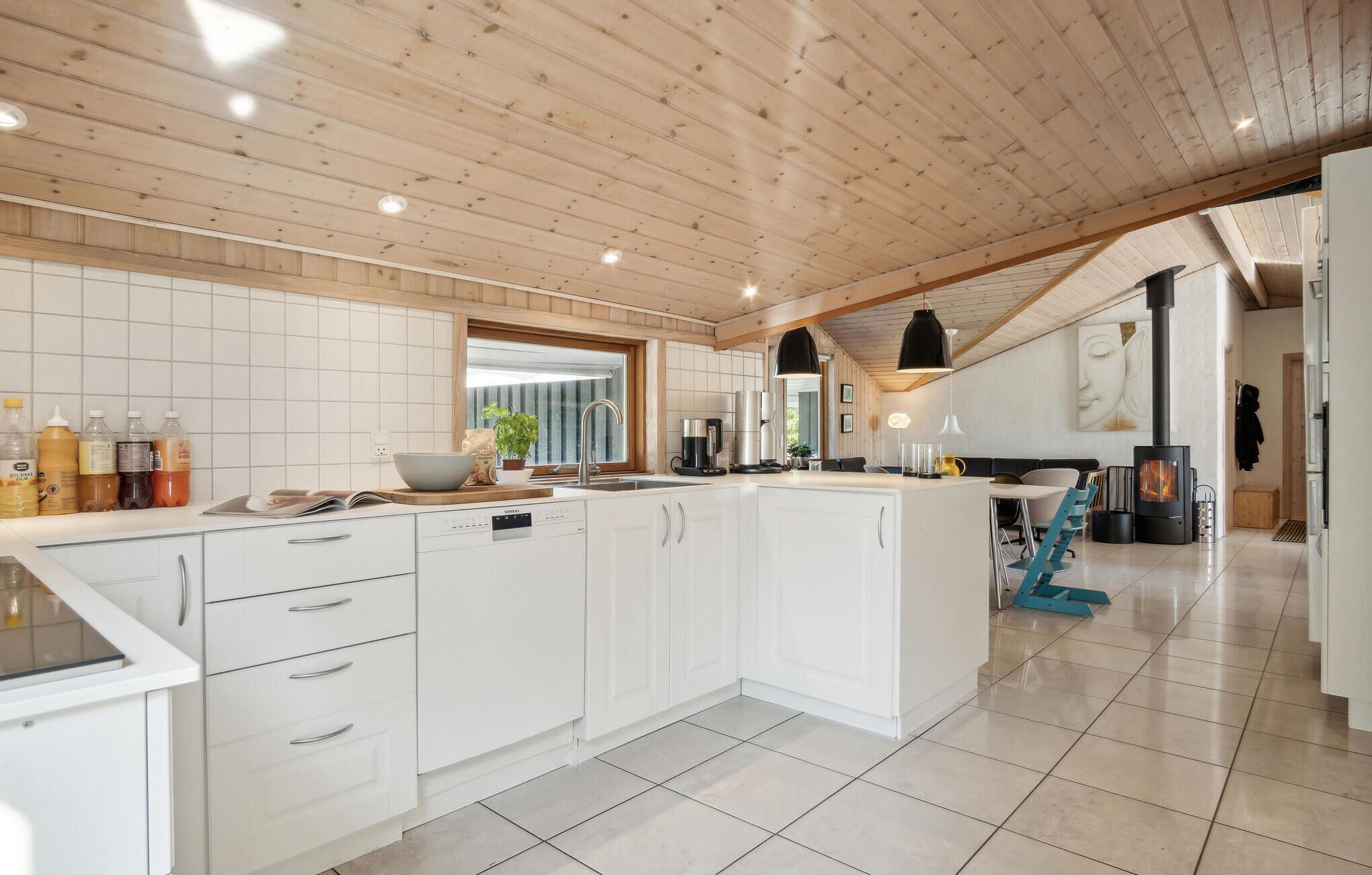 A modern kitchen with white cabinetry, a central island, and a dining area with a table and chairs.
