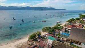 A coastal view with boats on the water, a beach, and buildings with a pool. - Marc Hotel Gili Trawangan (Gili Trawangan)