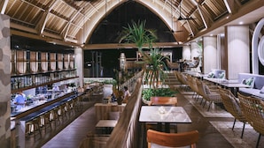 A spacious indoor area with high ceilings, a central seating area with tables and chairs, and a bar on the left. - Marc Hotel Gili Trawangan (Gili Trawangan)