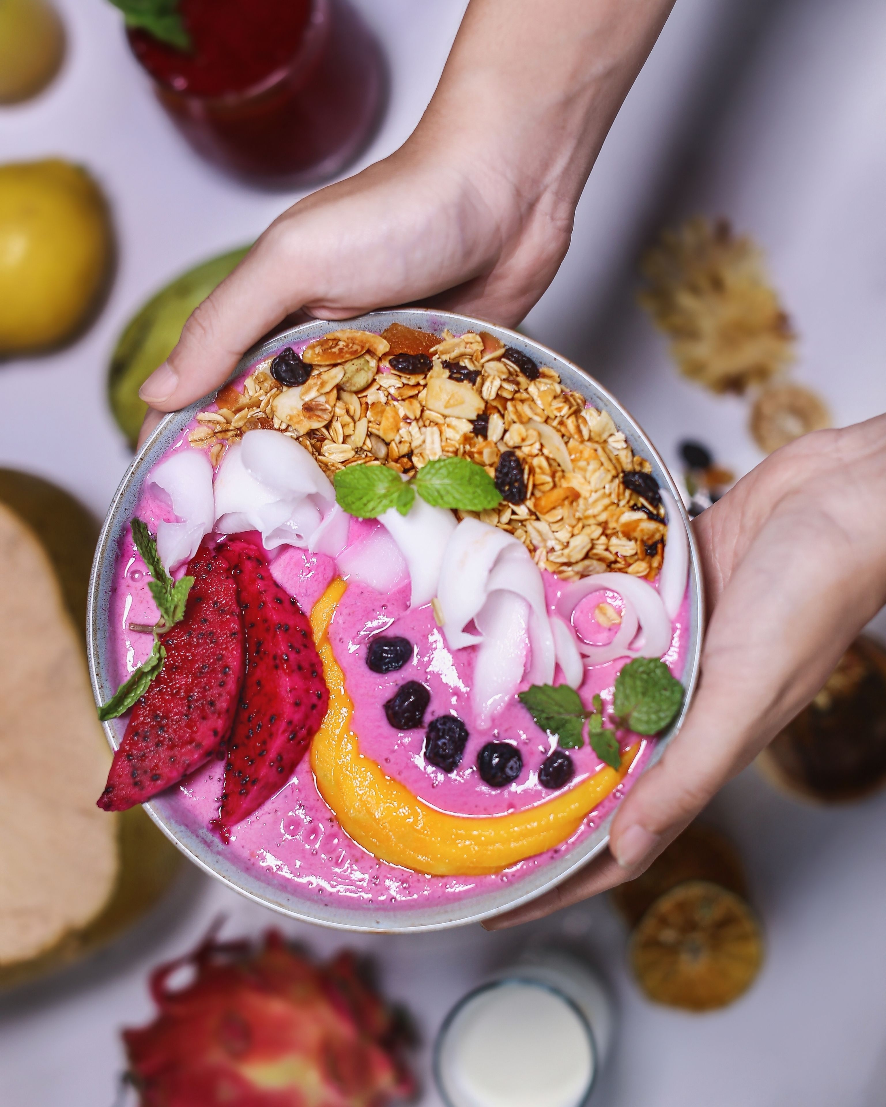 A person holding a bowl of colorful fruit and granola.
