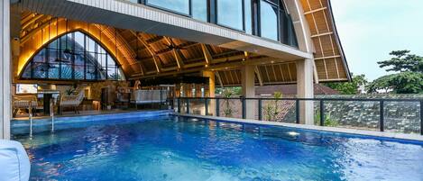 A swimming pool area with a covered seating area and a view of the surrounding landscape.