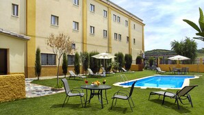 A hotel courtyard with a swimming pool, lounge chairs, and a small table with drinks. - Hotel Ciudad de Plasencia (Plasencia)