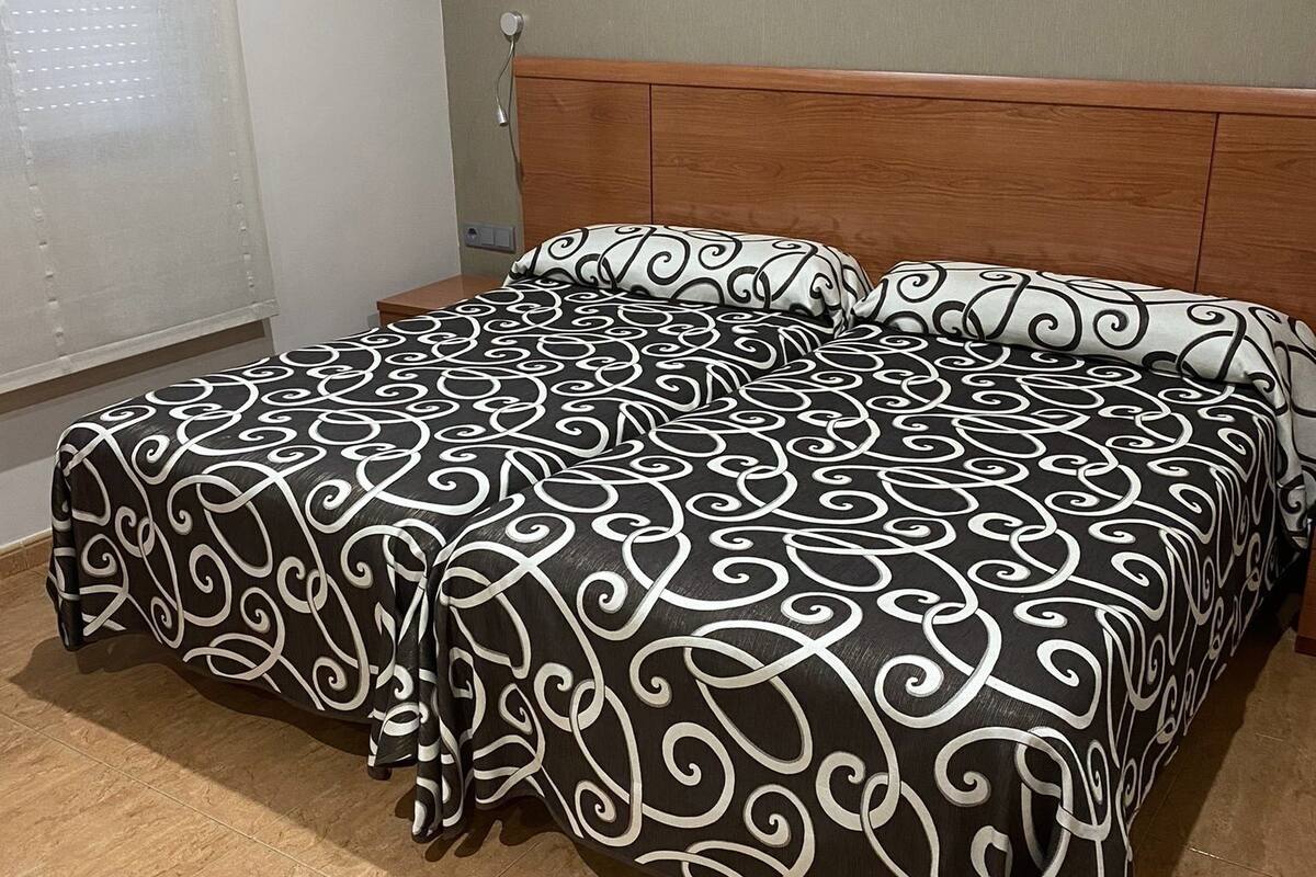 A bedroom with a bed, a wooden headboard, and a window with blinds.