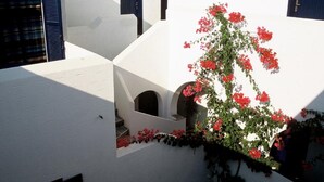 A white building with blue shutters, a staircase, and red flowers. - San Antonio Summer House by GHH (Paros)