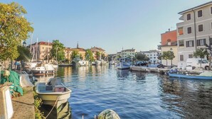 Un canal con barcos amarrados a ambos lados, rodeado de edificios con balcones y un cielo despejado.