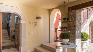 Zona de recepción con una escalera de piedra, un mostrador de recepción y un letrero en la pared.