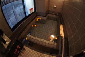 A bathroom with a bathtub, a window, and a tiled floor. - Economy Hotel Hoteiya (Tokyo)