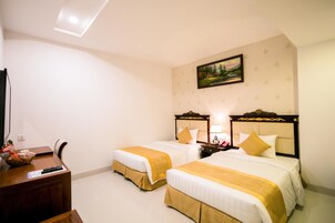 Una camera d'albergo con due letti, una scrivania, una TV e un quadro appeso al muro.