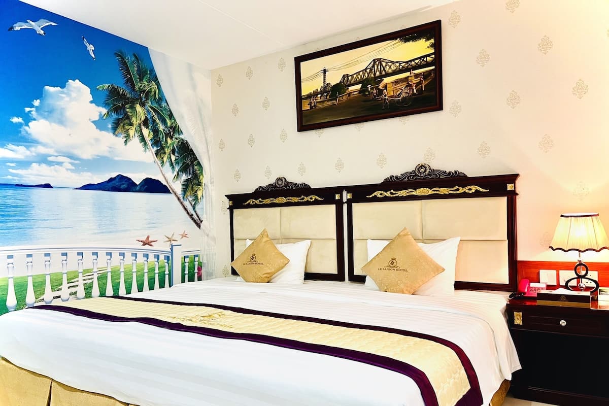 Hotelkamer met een bed, nachtkastje, lamp, schilderij en een muurschildering van een strand.