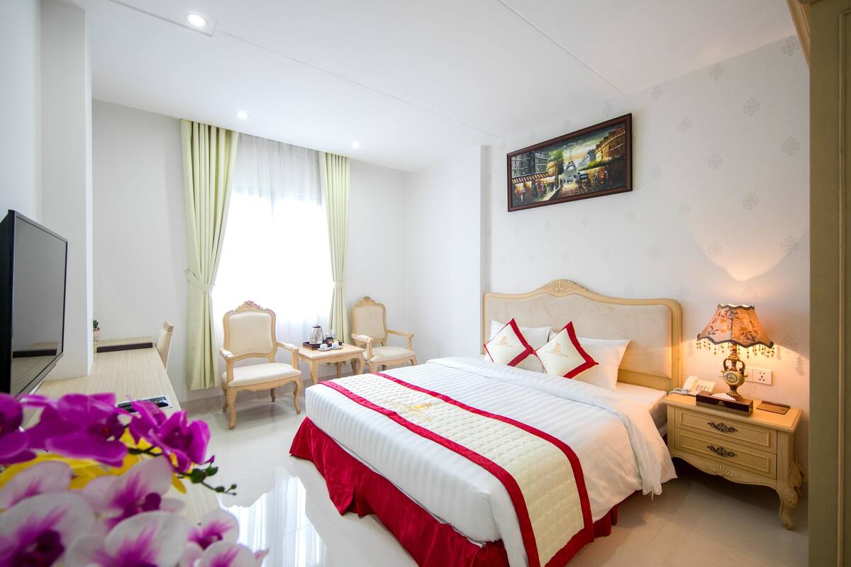 Een hotelkamer met een groot bed, een televisie, een bureau en een stoel.