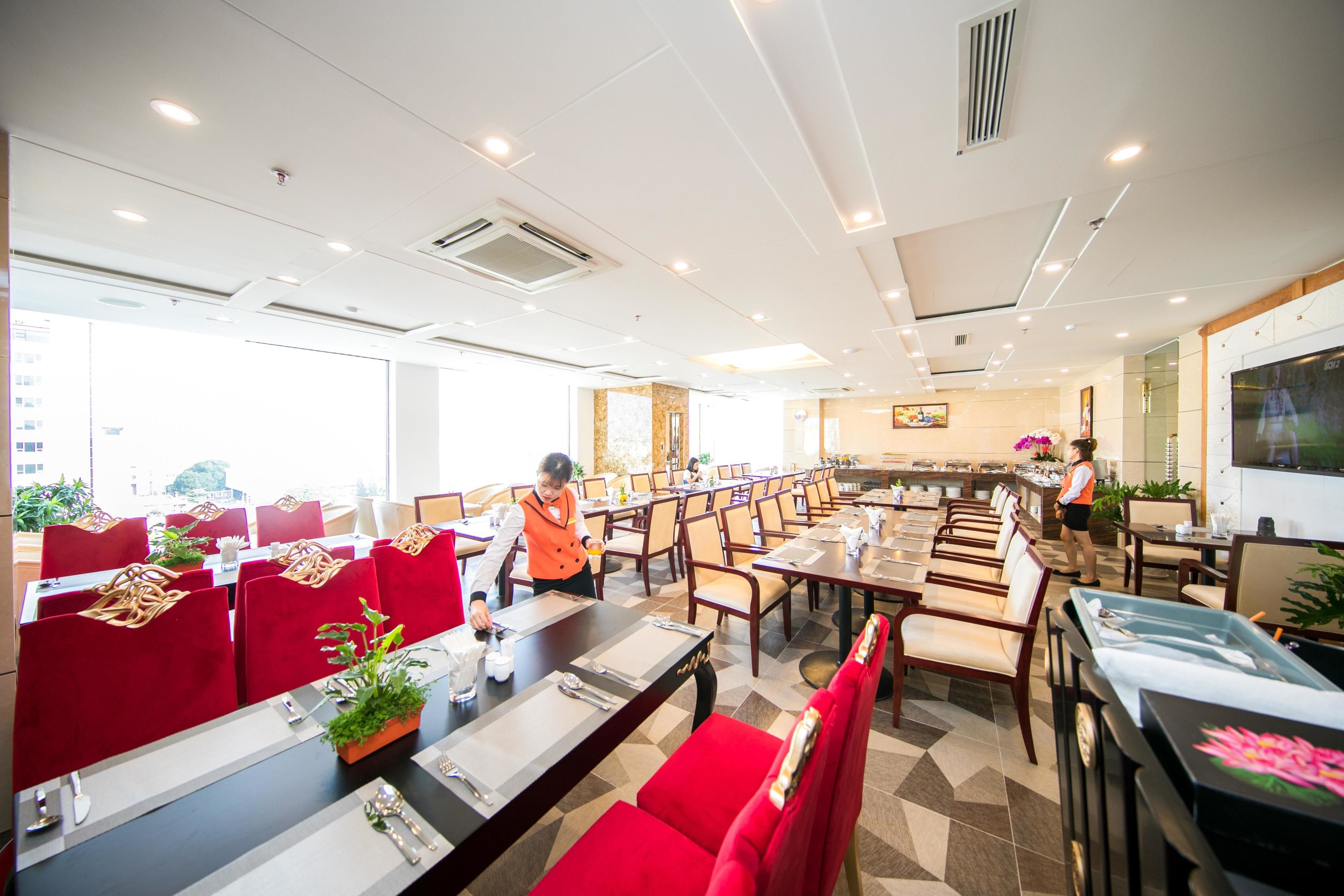 A spacious dining area with multiple tables and chairs, a buffet setup, and a large window providing natural light.