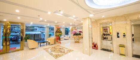 A spacious lobby with a polished floor, a central floral arrangement, and a modern chandelier.