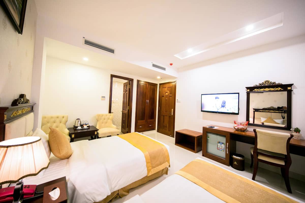 Een hotelkamer met een bed, een bureau, een stoel, een televisie en een spiegel.