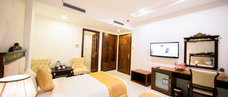 A hotel room with a bed, a desk, a chair, a television, and a mirror.