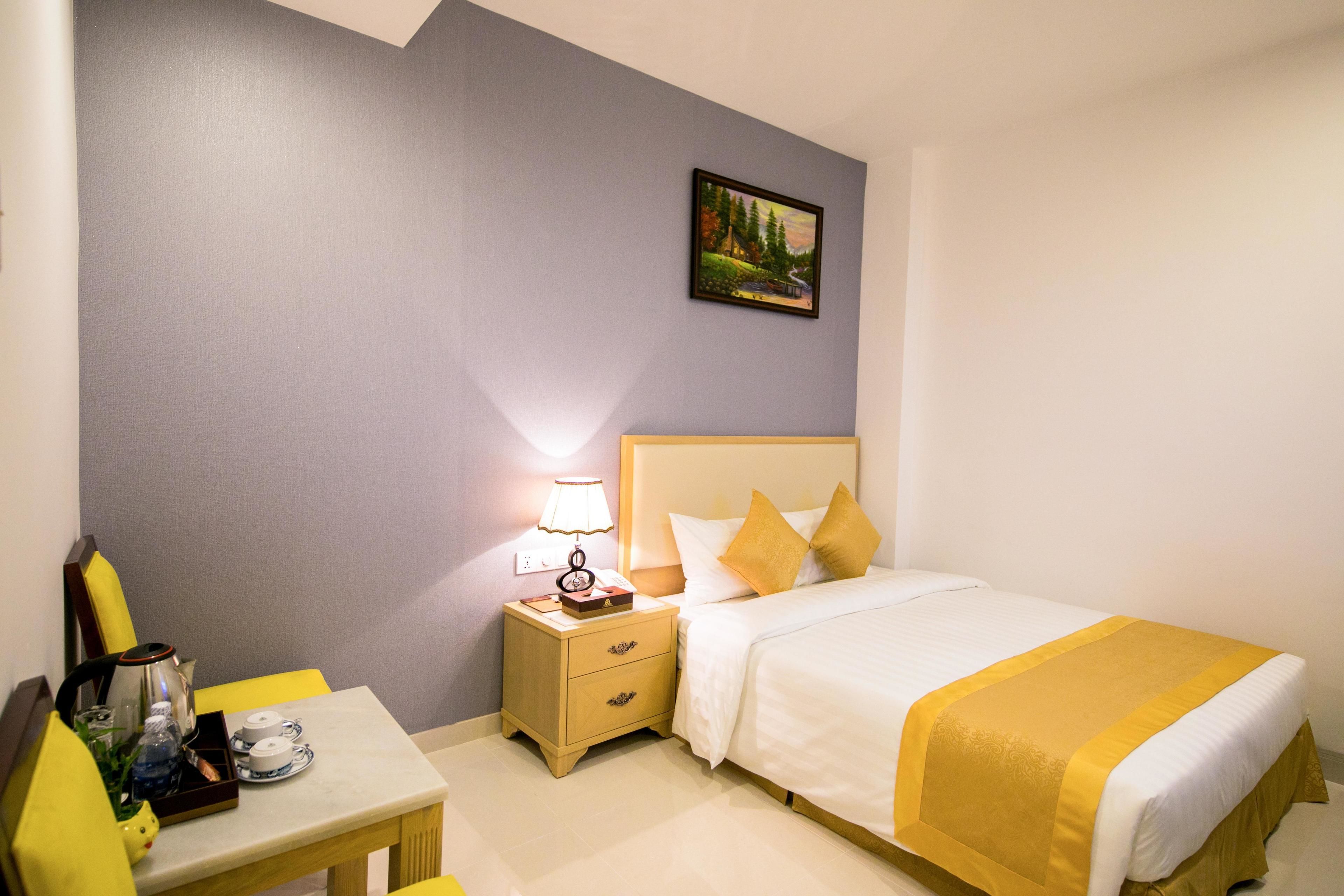 Ein Hotelzimmer mit Bett, Nachttisch, Lampe und einem Bild an der Wand.