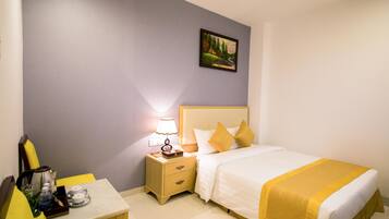 Ein Hotelzimmer mit Bett, Nachttisch, Lampe und einem Bild an der Wand.