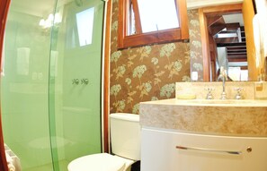 A bathroom with a glass shower enclosure, a toilet, and a sink with a mirror.