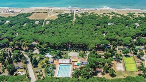 Vue aérienne d’un complexe hôtelier doté d’une grande piscine, de courts de tennis et d’une plage.