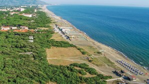 Une vue aérienne d’une zone côtière avec une plage, des bâtiments et de la végétation.