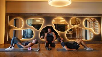 Three people exercising on mats in a room with wooden flooring and a unique wall design.