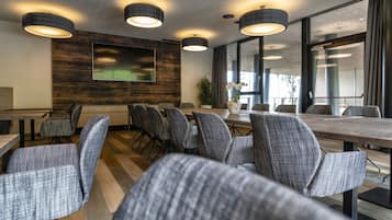 A conference room with grey upholstered chairs, a wooden table, and pendant lighting.