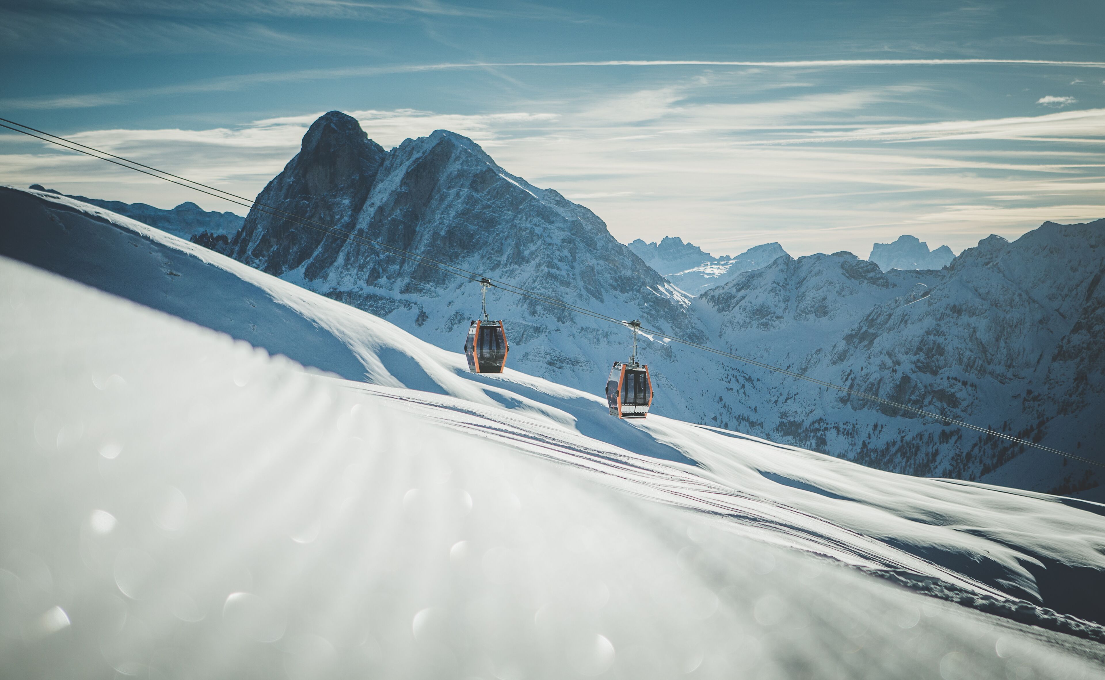 A snowy mountain landscape with two cable cars.