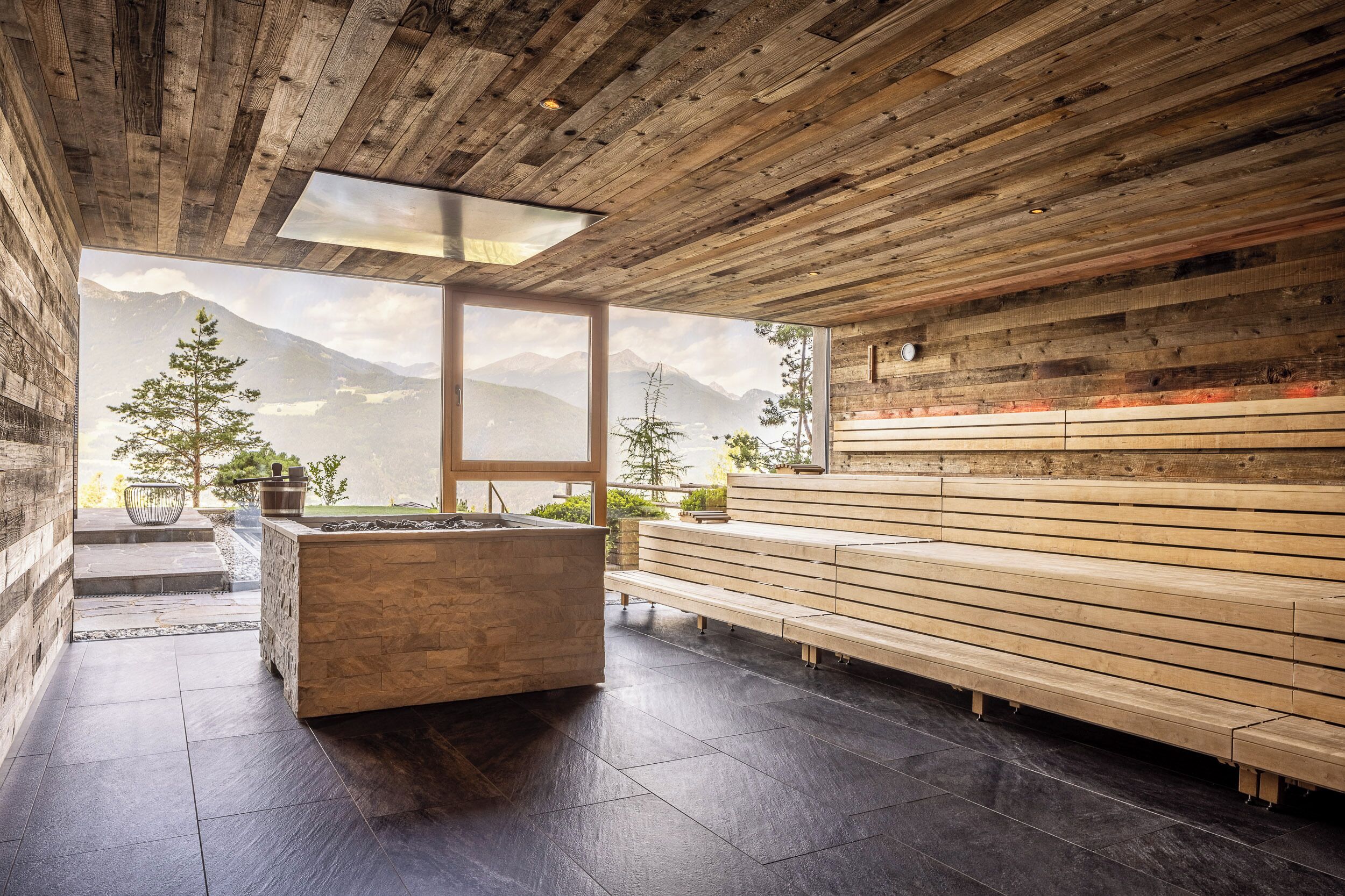 A modern interior with wooden panel walls, a stone fireplace, and a bench area.