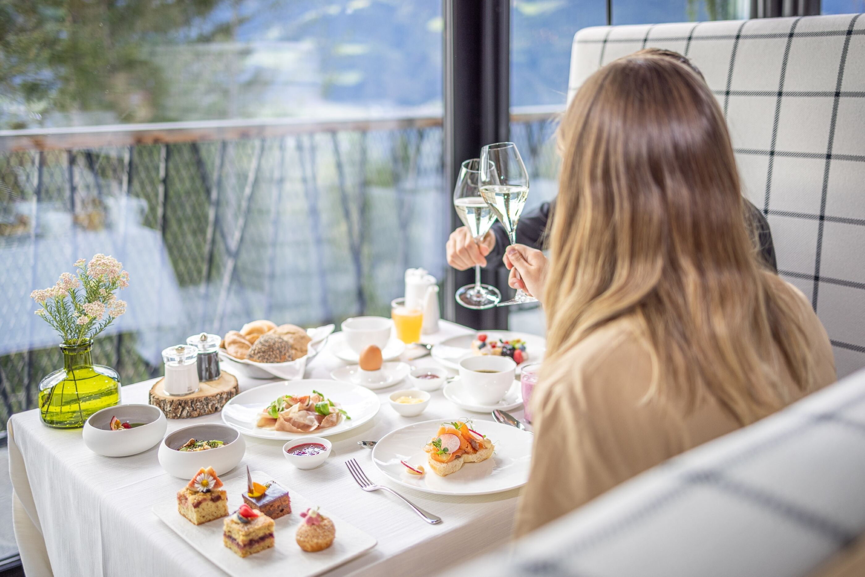 A dining table set with various dishes, a vase with flowers, and a window view.