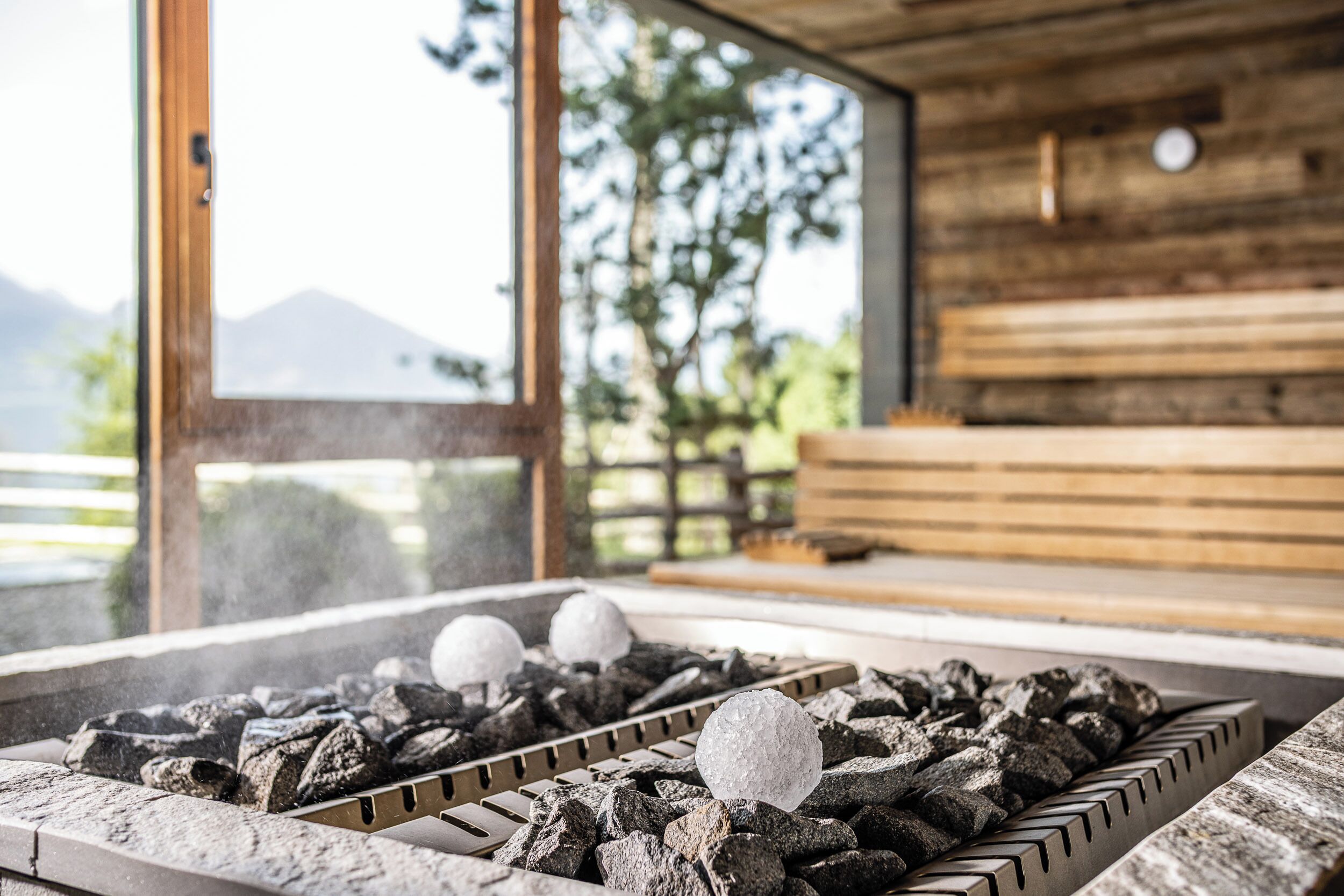 A sauna with a wooden interior, a large window, and a view of mountains.