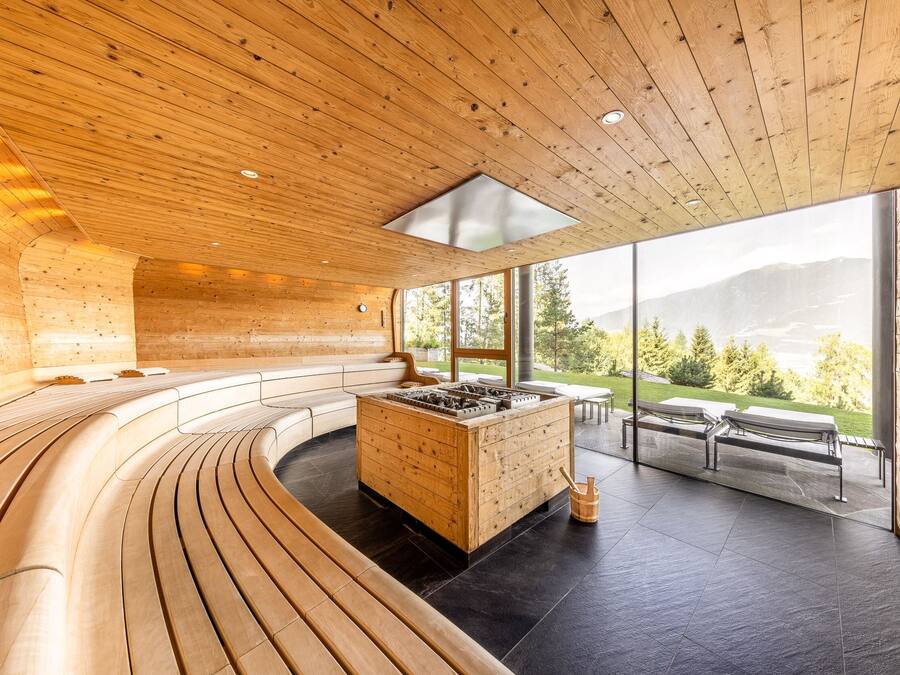 Un interior moderno con paneles de madera, una estructura central de madera y vistas a un paisaje montañoso a través de amplios ventanales.