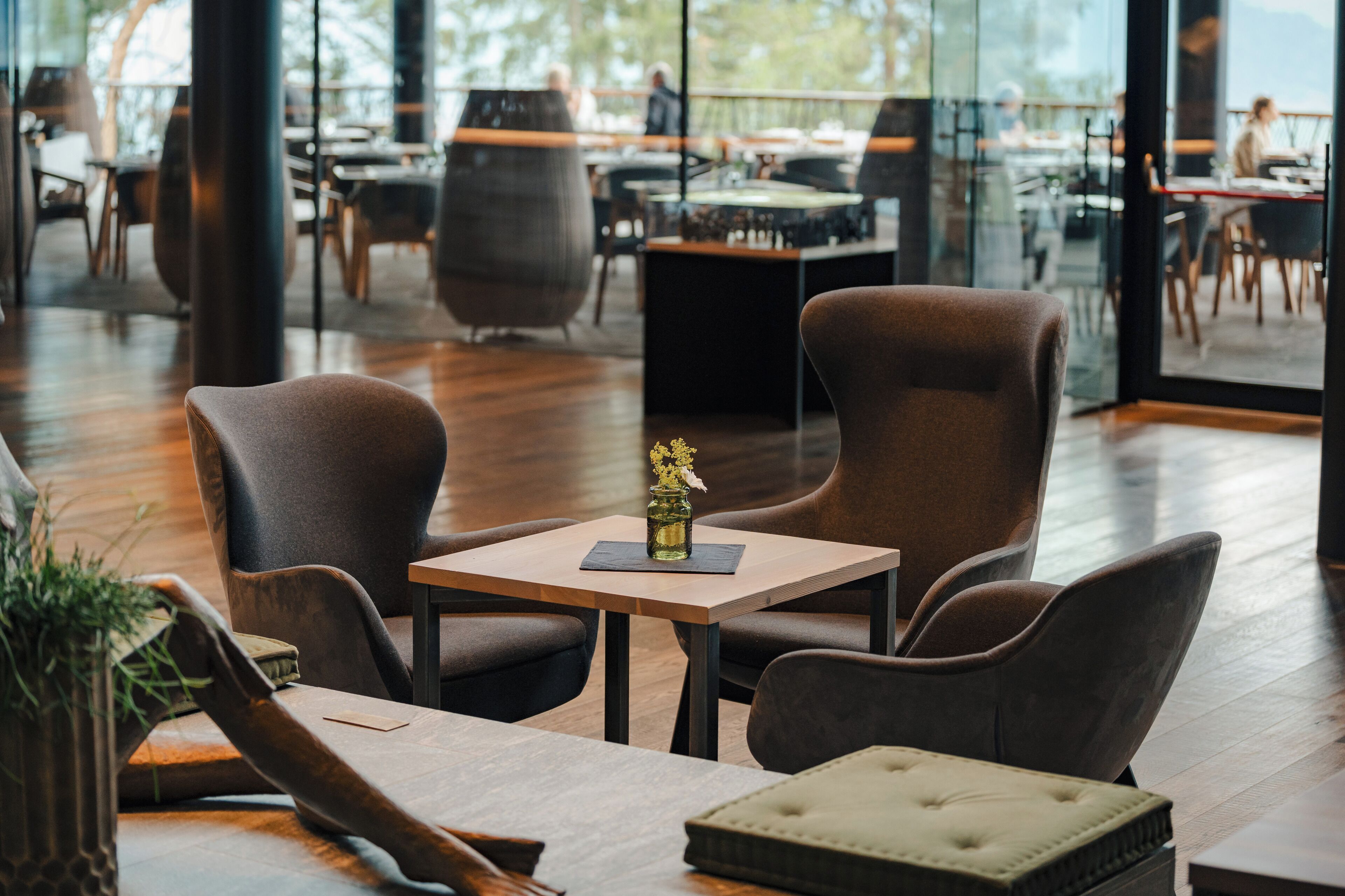 A modern dining area with wooden flooring, leather chairs, and a small table with a vase.
