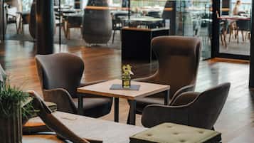 A modern dining area with wooden flooring, leather chairs, and a small table with a vase.