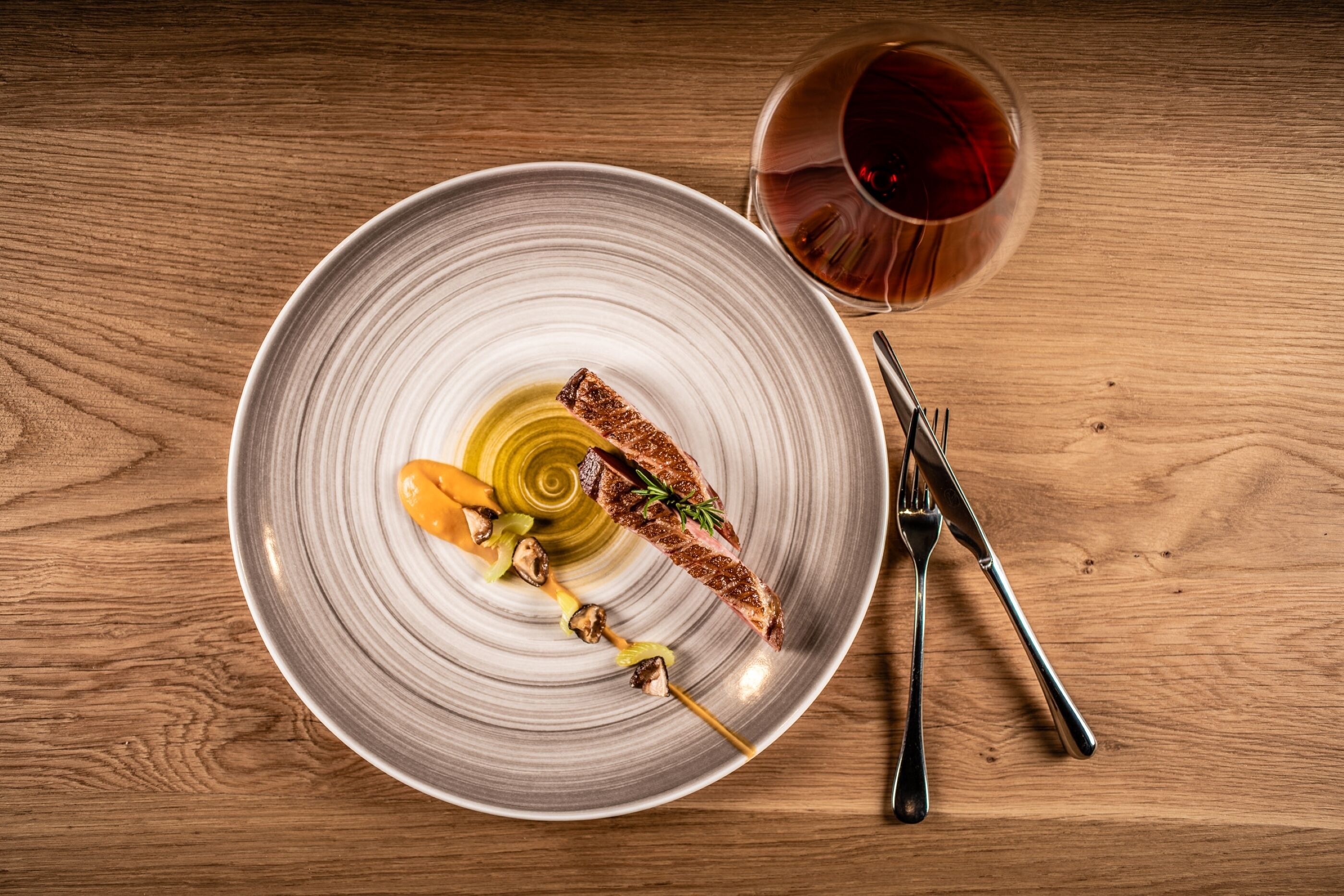 Une assiette contenant un steak grillé, des champignons et une brochette de légumes, le tout posé sur une table en bois.