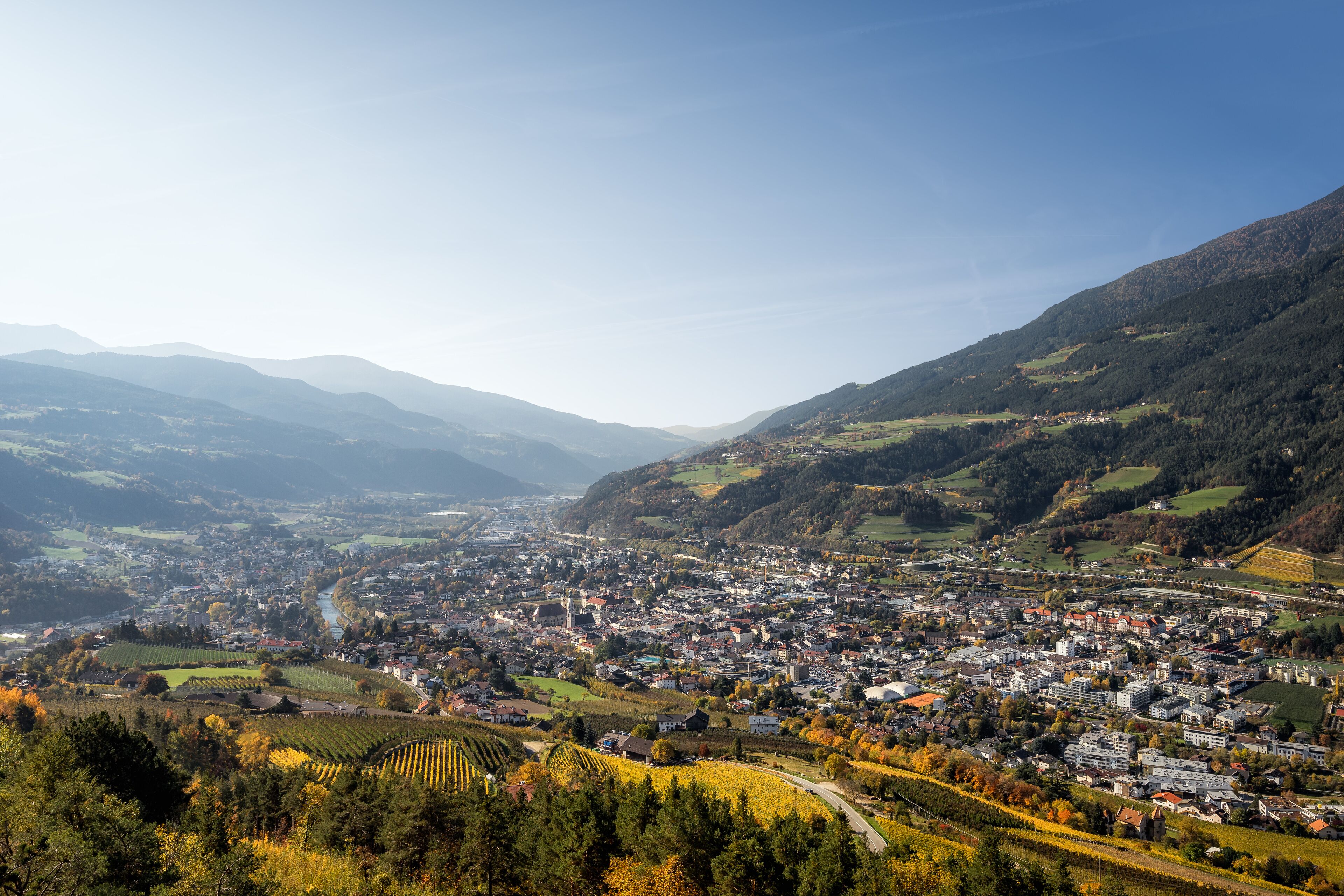 A town nestled in a valley with a river running through it, surrounded by hills.