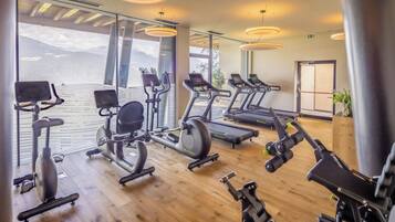 Ein Fitnessstudio mit verschiedenen Trainingsgeräten, großen Fenstern und Bergblick.
