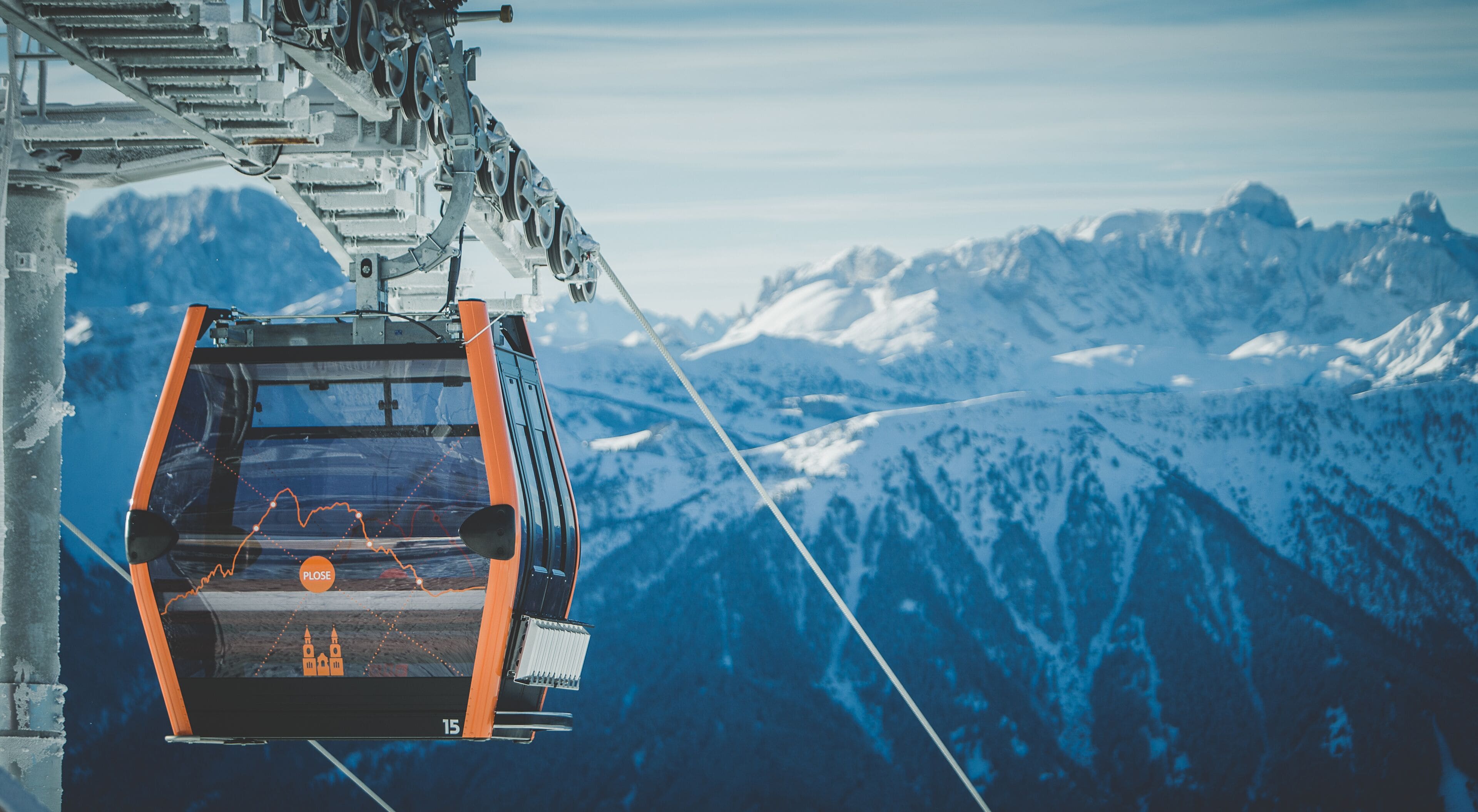 A cable car suspended over a snowy mountain range.