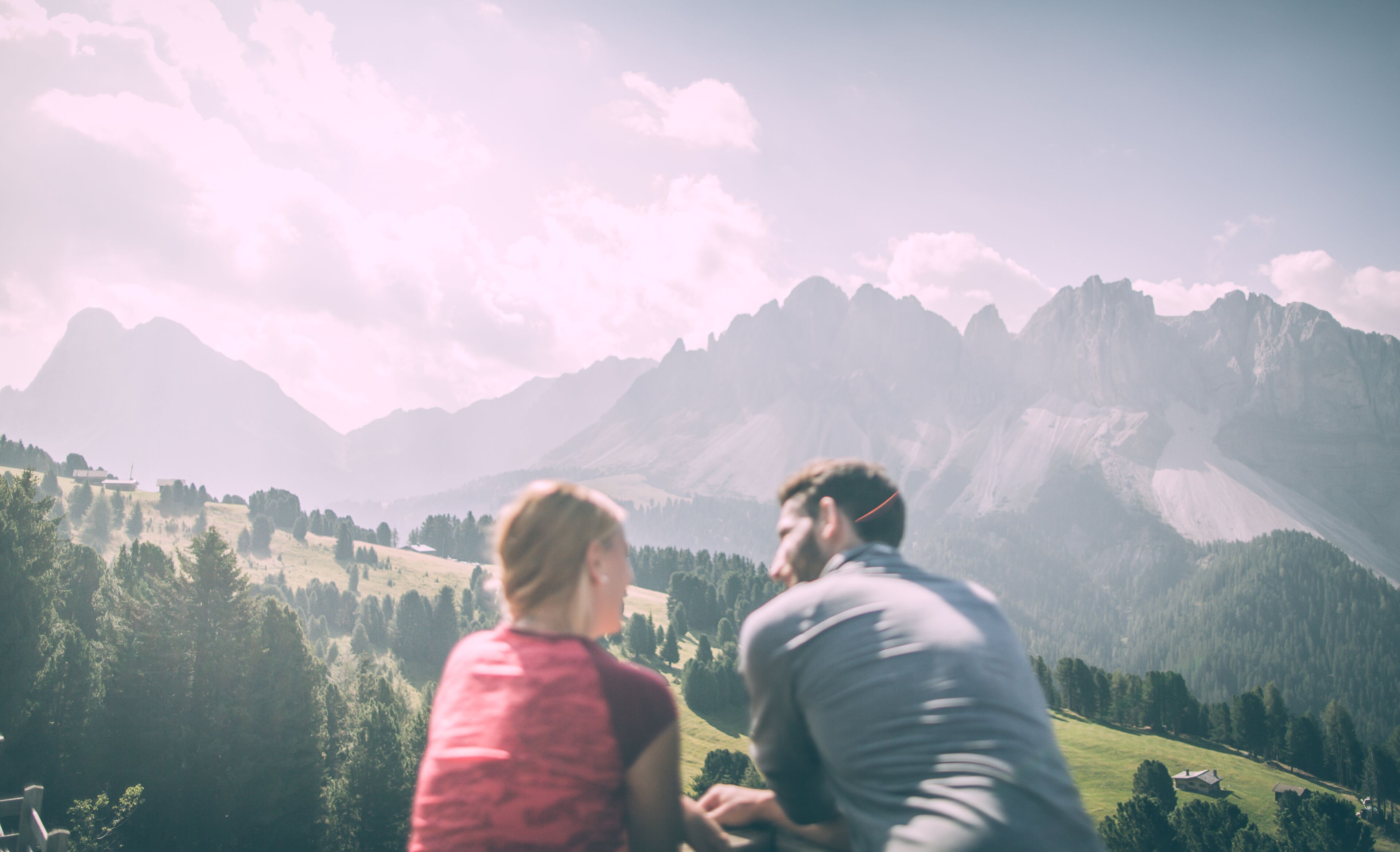 A couple overlooking a mountainous landscape with a view of the valley below.